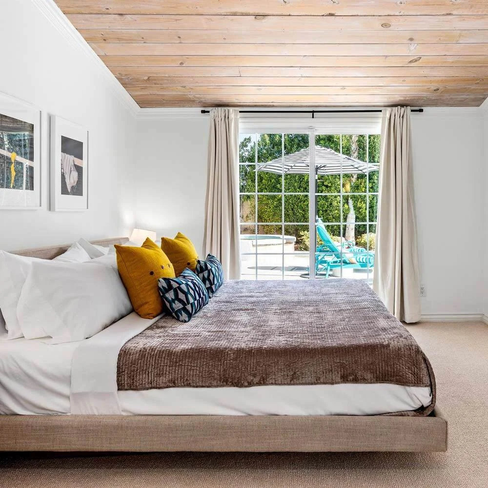 A king sized bed with a window overlooking the pool