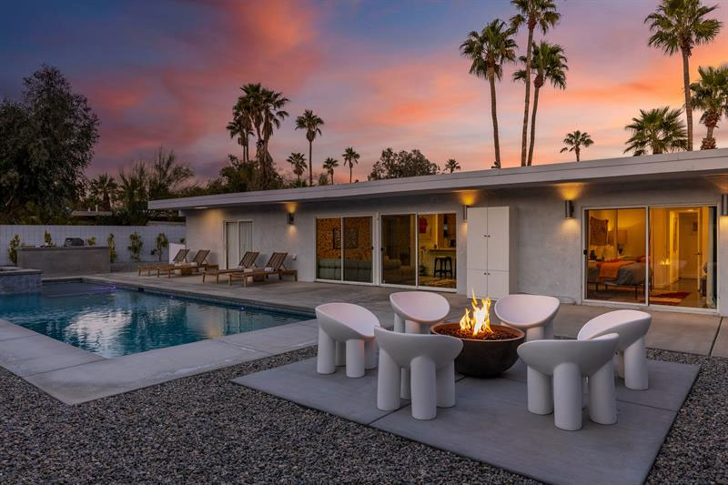 Photo of a poolside firepit and chairs at sunset